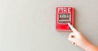 person pointing at fire alarm